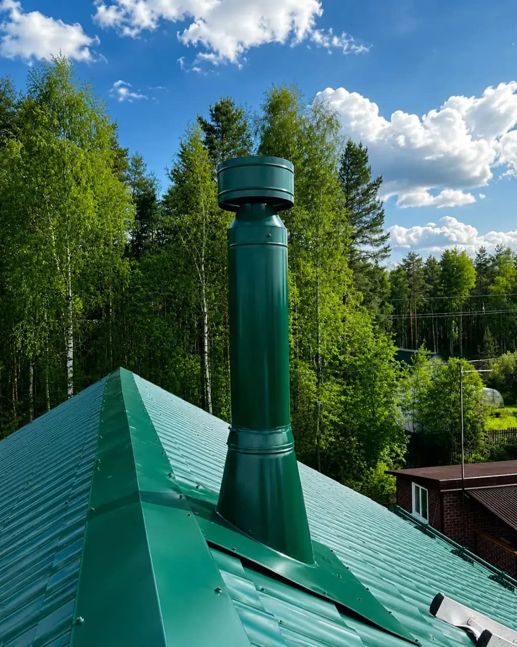 Зелёный металлический дымоход над кровлей